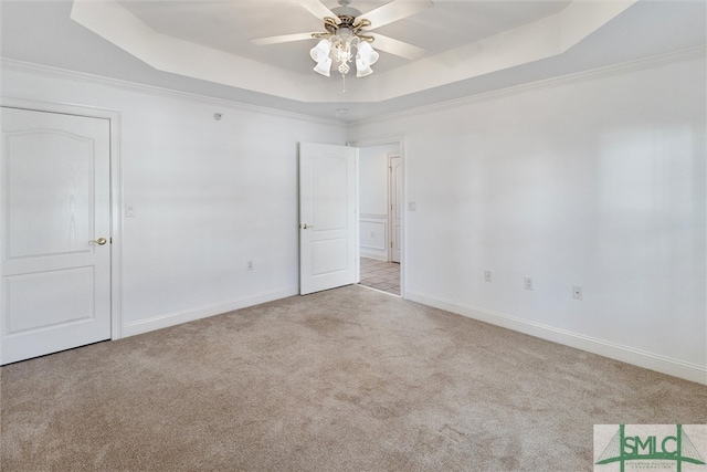 spare room with crown molding, light carpet, a tray ceiling, and ceiling fan