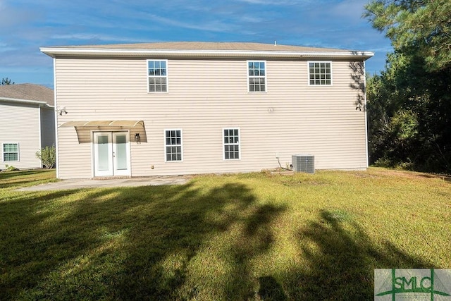 back of property with a lawn and central AC