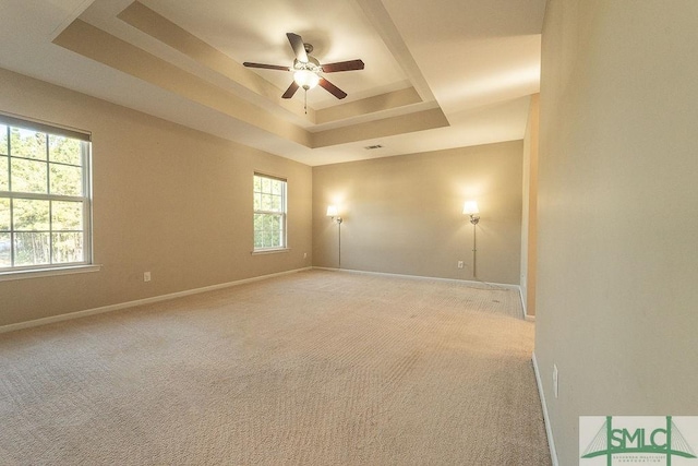 unfurnished room featuring light carpet, baseboards, and a tray ceiling