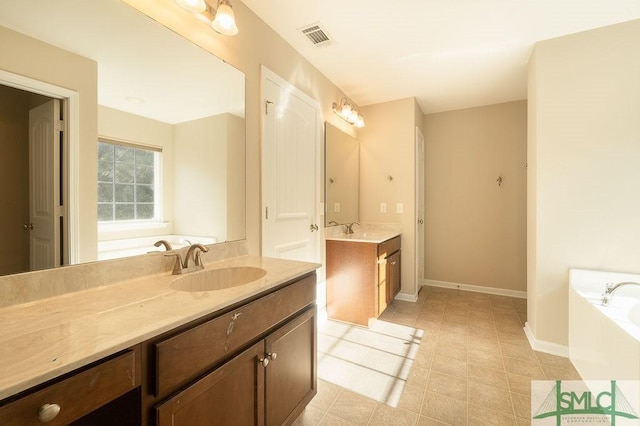 bathroom with a garden tub, two vanities, a sink, and visible vents