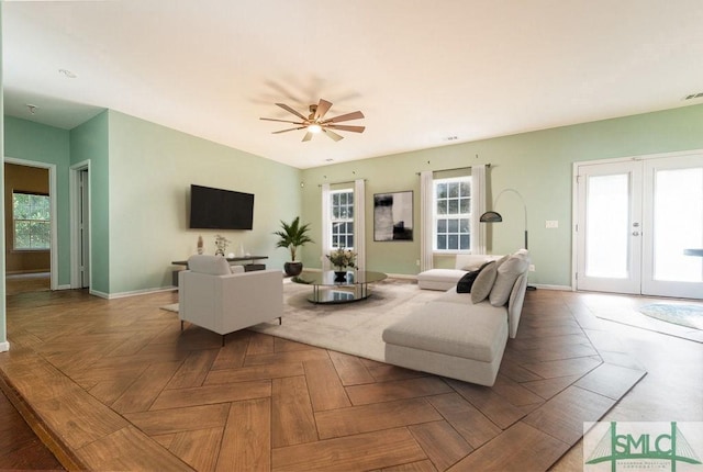 living area with french doors, ceiling fan, and baseboards