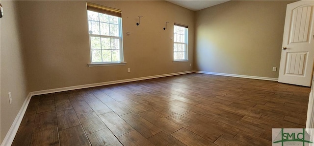 empty room with baseboards, dark wood-type flooring, and a healthy amount of sunlight