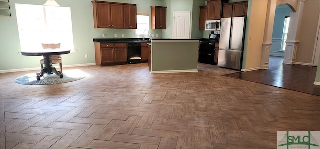 kitchen featuring dark countertops, black appliances, arched walkways, and a center island