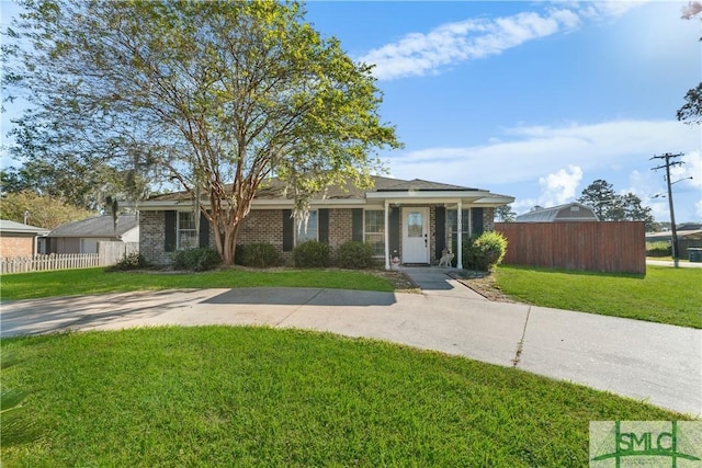 view of front of property featuring driveway, brick siding, a front lawn, and fence