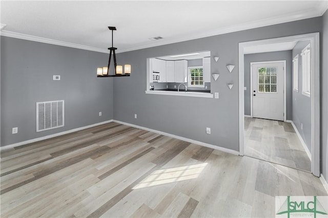 unfurnished dining area with visible vents, light wood-style floors, a healthy amount of sunlight, and crown molding