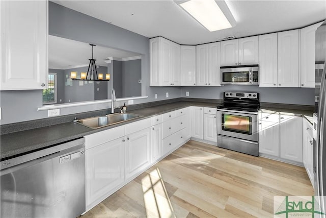 kitchen with a sink, dark countertops, white cabinetry, and stainless steel appliances