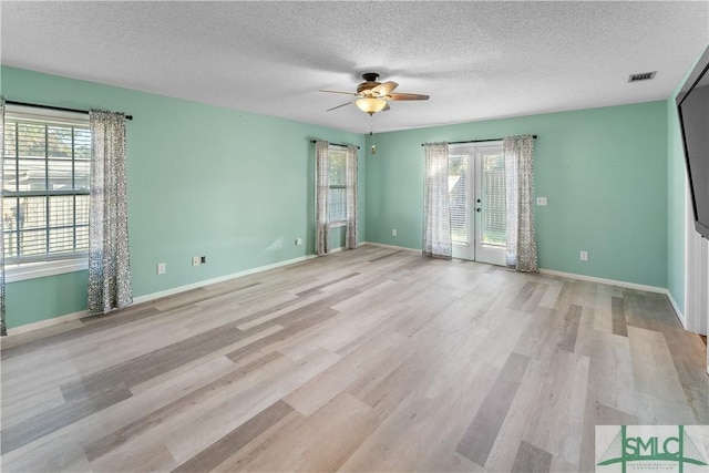 empty room featuring visible vents, plenty of natural light, french doors, and light wood-style floors