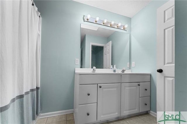 bathroom featuring tile patterned floors, a sink, baseboards, and double vanity