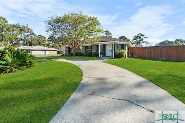 view of front facade featuring driveway, brick siding, a front lawn, and fence