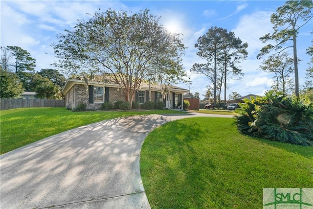 view of front of home with brick siding, a front lawn, and fence