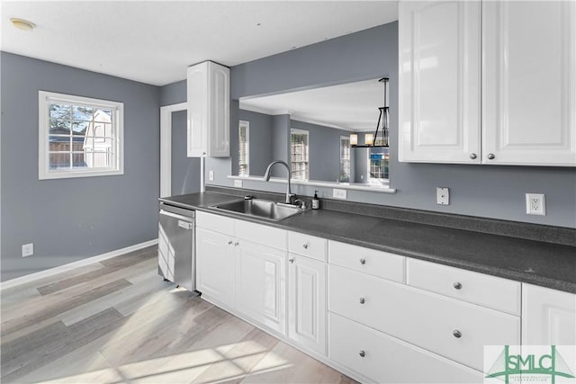 kitchen featuring a sink, stainless steel dishwasher, dark countertops, and white cabinetry