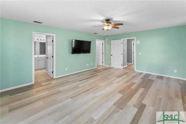 interior space featuring visible vents, ceiling fan, baseboards, light wood-style floors, and ensuite bath