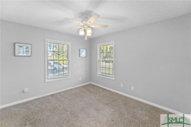 carpeted empty room featuring a ceiling fan and baseboards