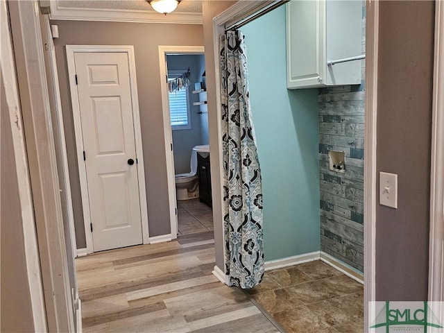 hall with crown molding, light wood-style flooring, and baseboards