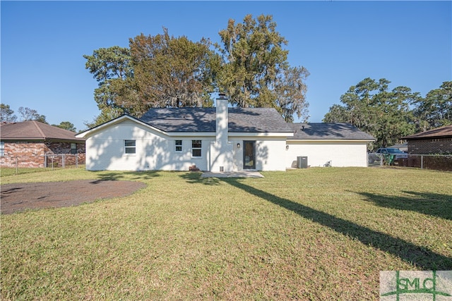 back of property with central air condition unit and a lawn