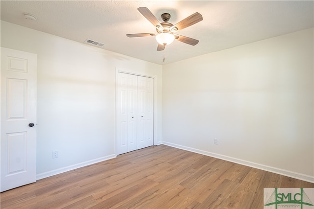 unfurnished bedroom featuring a closet, a textured ceiling, light wood-type flooring, and ceiling fan