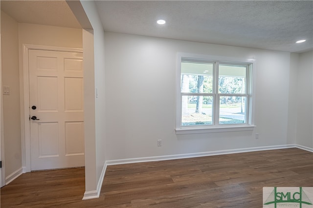 spare room with a textured ceiling and dark hardwood / wood-style floors