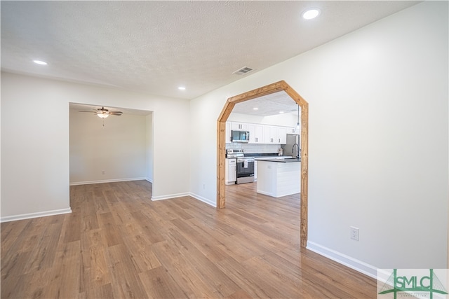 spare room with light hardwood / wood-style flooring, a textured ceiling, sink, and ceiling fan