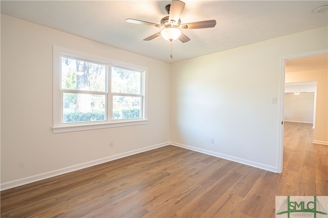 unfurnished room with ceiling fan, wood-type flooring, and a textured ceiling