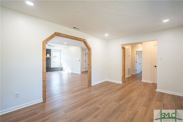 spare room with a textured ceiling and light hardwood / wood-style flooring