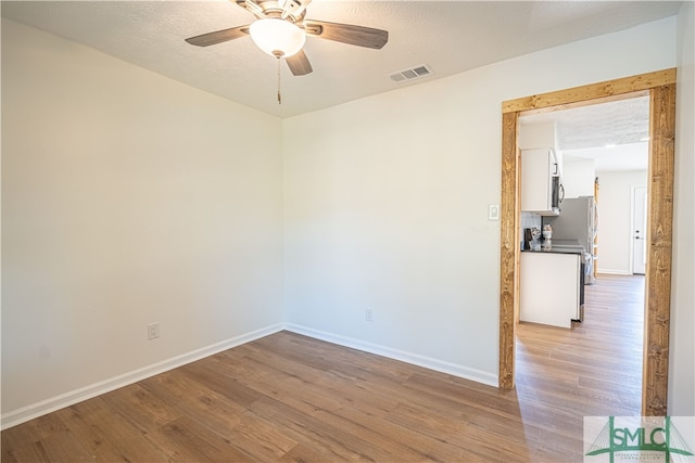 unfurnished room with light hardwood / wood-style floors, a textured ceiling, and ceiling fan