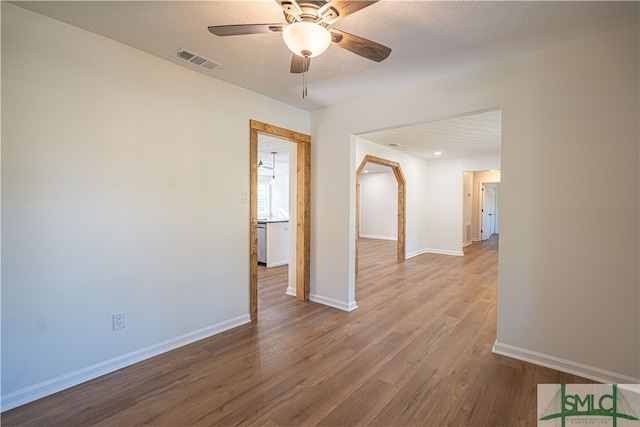 unfurnished room with ceiling fan, hardwood / wood-style flooring, and a textured ceiling