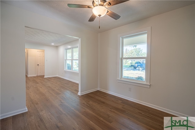 spare room with a textured ceiling, ceiling fan, and dark hardwood / wood-style flooring