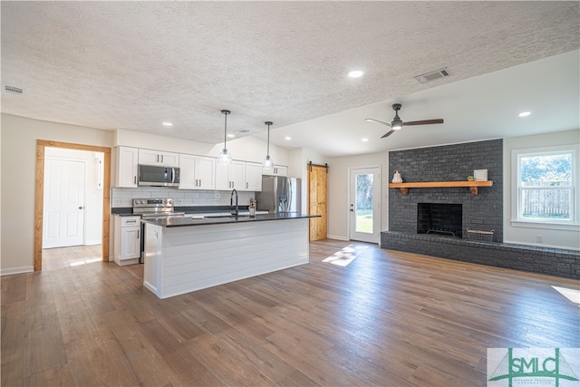 kitchen with a wealth of natural light, pendant lighting, white cabinets, and stainless steel appliances