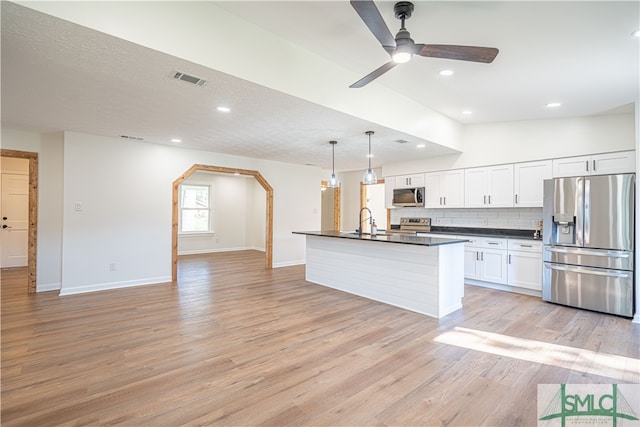 kitchen featuring hanging light fixtures, stainless steel appliances, a center island with sink, white cabinets, and light hardwood / wood-style floors