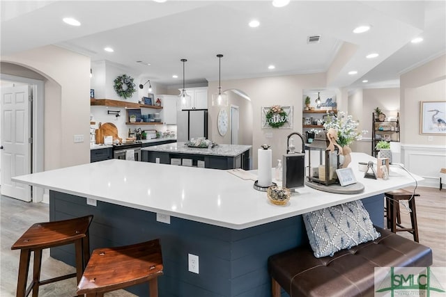 2203 River Oaks Dr, Richmond Hill, GA 31324 - kitchen featuring a large island, open shelves, crown molding, arched walkways, and freestanding refrigerator