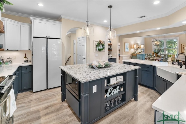 2203 River Oaks Dr, Richmond Hill, GA 31324 - kitchen featuring light wood finished floors, a sink, open shelves, ornamental molding, and freestanding refrigerator