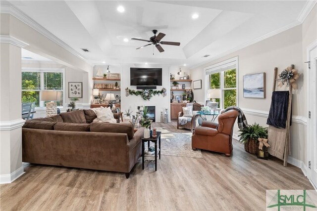2203 River Oaks Dr, Richmond Hill, GA 31324 - living room with light wood-type flooring, a raised ceiling, a ceiling fan, and a glass covered fireplace
