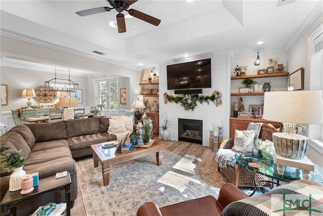 2203 River Oaks Dr, Richmond Hill, GA 31324 - living area with a raised ceiling, visible vents, wood finished floors, and ceiling fan with notable chandelier