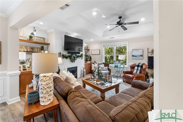2203 River Oaks Dr, Richmond Hill, GA 31324 - living room featuring visible vents, light wood-type flooring, ornamental molding, a fireplace, and a ceiling fan