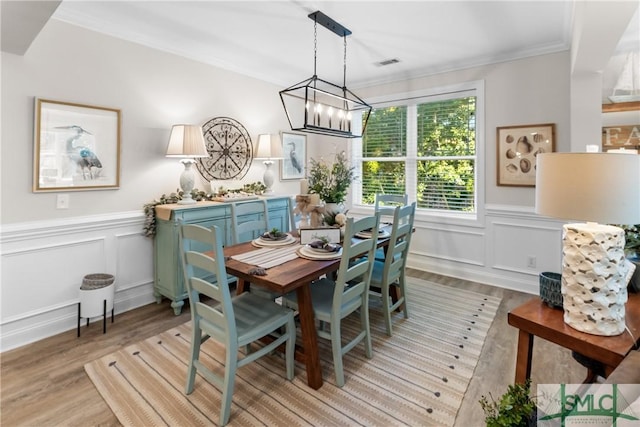 2203 River Oaks Dr, Richmond Hill, GA 31324 - dining area featuring an inviting chandelier, a wainscoted wall, crown molding, and light wood finished floors