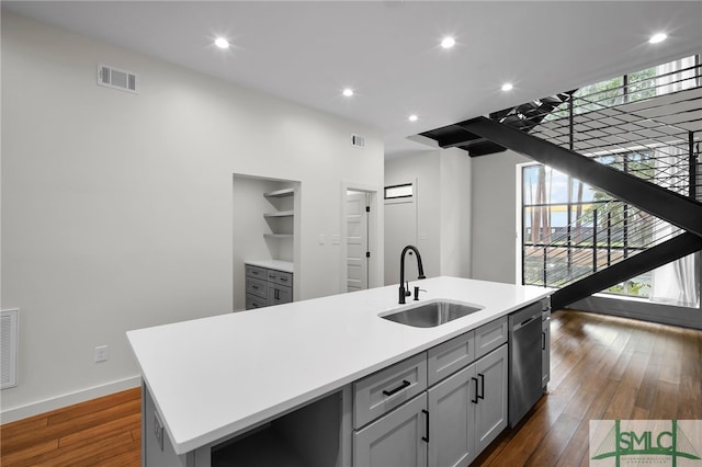 kitchen featuring stainless steel dishwasher, sink, a center island with sink, and dark hardwood / wood-style flooring