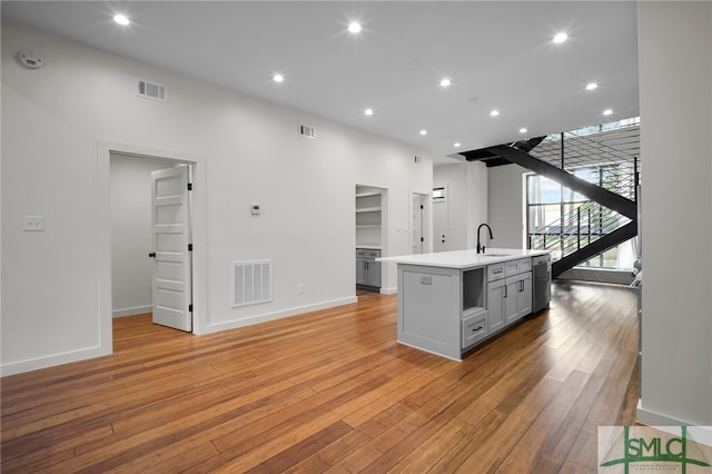 kitchen featuring sink, light hardwood / wood-style flooring, an island with sink, and gray cabinetry