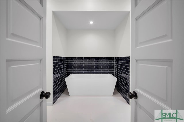 bathroom with a bathing tub, tile walls, and tile patterned flooring