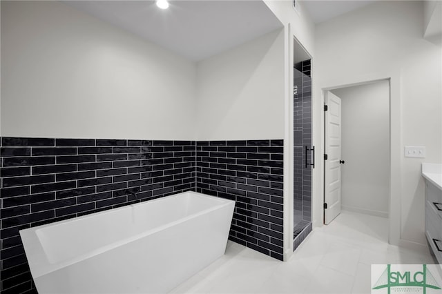 bathroom with vanity, tile walls, and separate shower and tub