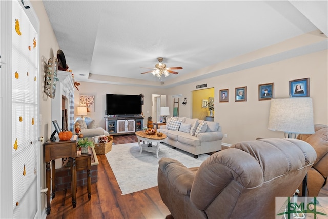 living room with wood-type flooring, a tray ceiling, and ceiling fan