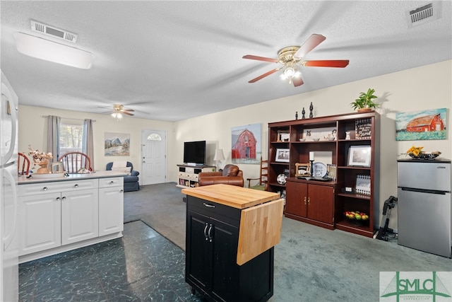 carpeted office space featuring a textured ceiling and ceiling fan