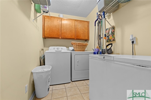 laundry room with cabinets, independent washer and dryer, a textured ceiling, and light tile patterned floors