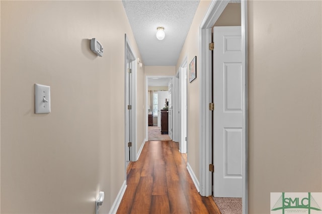 hall with a textured ceiling and dark hardwood / wood-style floors