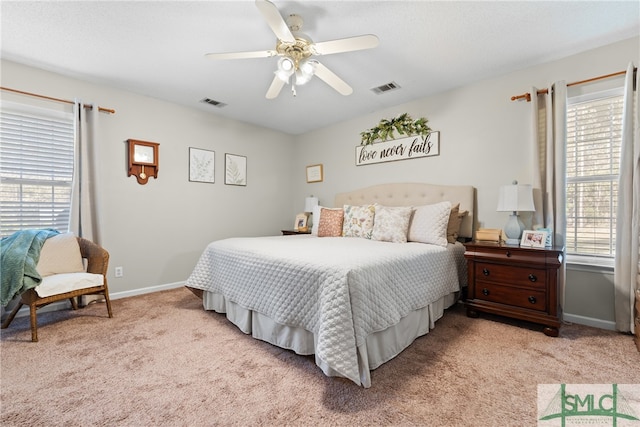 bedroom with ceiling fan, multiple windows, and light colored carpet