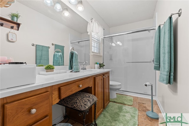 bathroom with a shower with door, vanity, and toilet