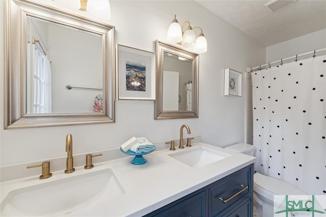 bathroom with toilet, vanity, a textured ceiling, and walk in shower