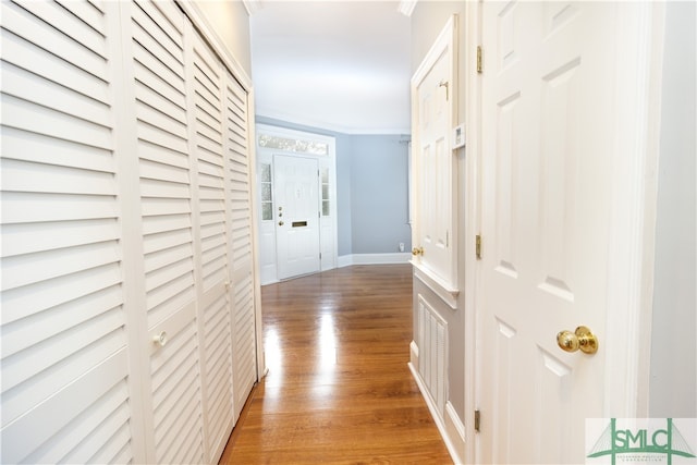 hallway with ornamental molding and wood-type flooring