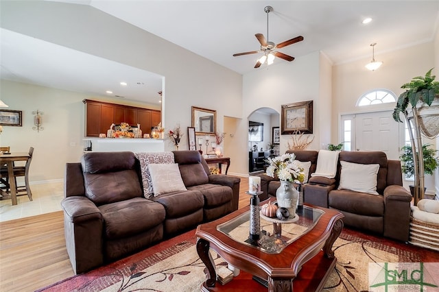 living room featuring light hardwood / wood-style floors, crown molding, high vaulted ceiling, and ceiling fan