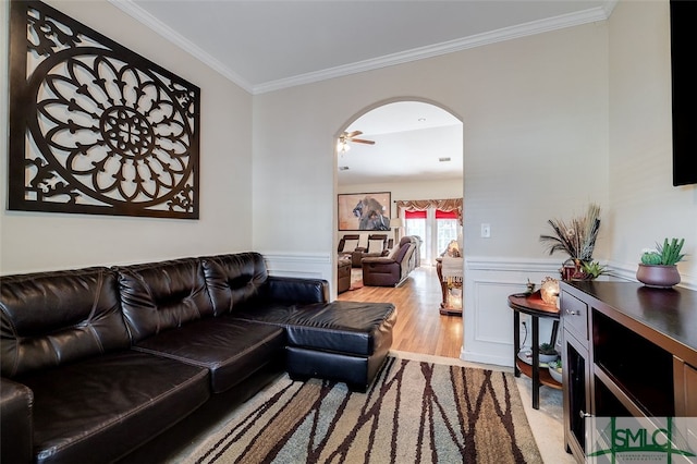 living room featuring ceiling fan, ornamental molding, and light wood-type flooring