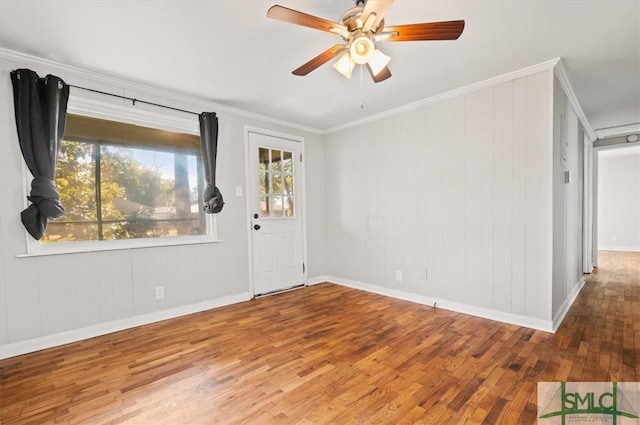 interior space featuring wood-type flooring, wooden walls, ceiling fan, and ornamental molding